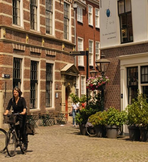 vrouw fiets door straat met oude huizen