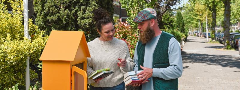 man en vrouw bekijken boeken in minibieb op straat